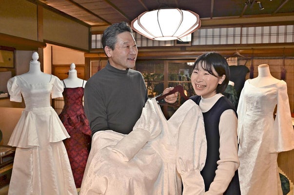 手作りしたドレスを手に笑顔を見せる堀井さん（右）と父・正彦さん（京都市中京区で）＝永尾泰史撮影