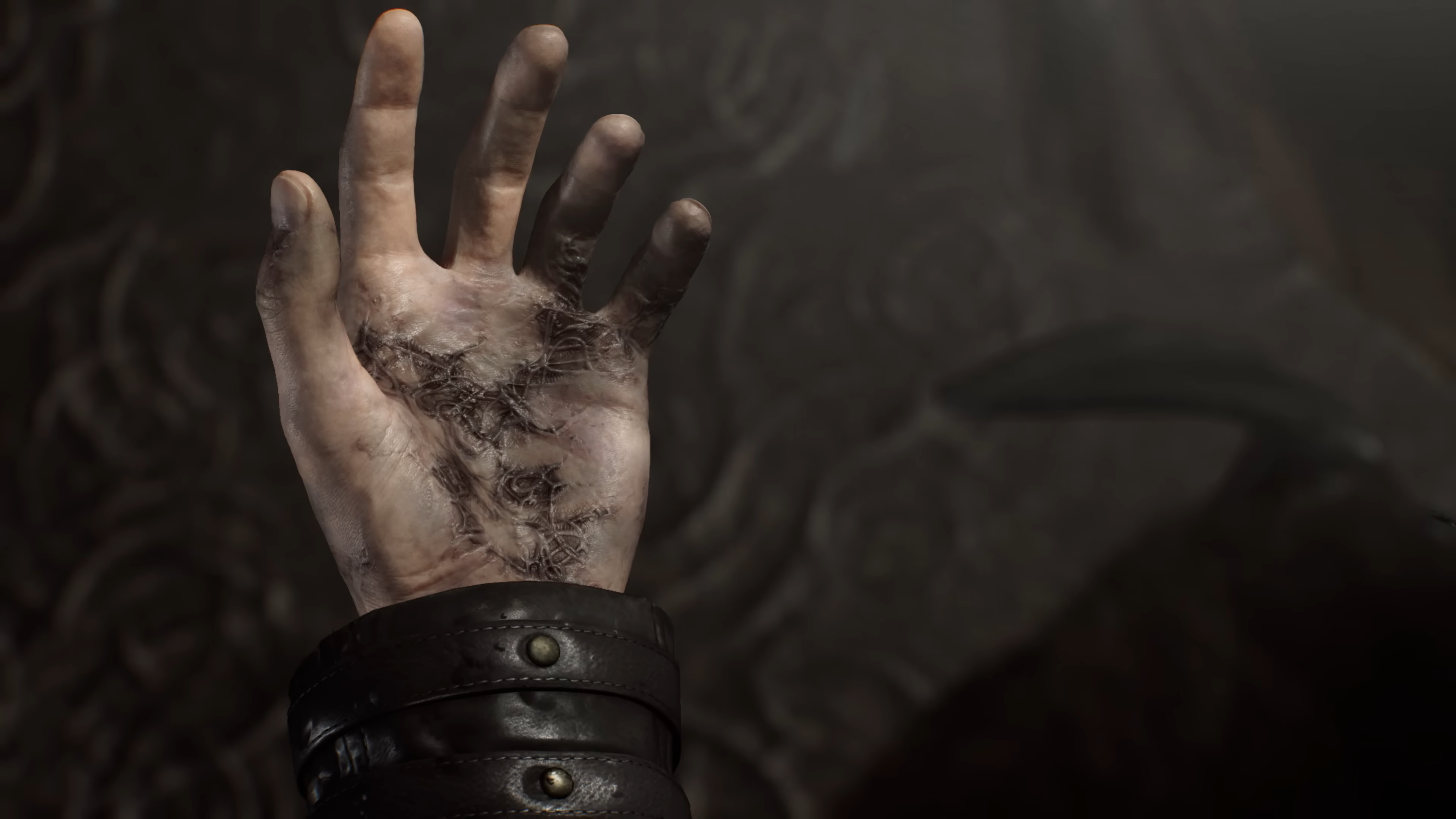 グローブを外したレオンの左手には、黒い痣と細長い形状の寄生虫がいるかのような痕がある。画像は4th Trailerより。