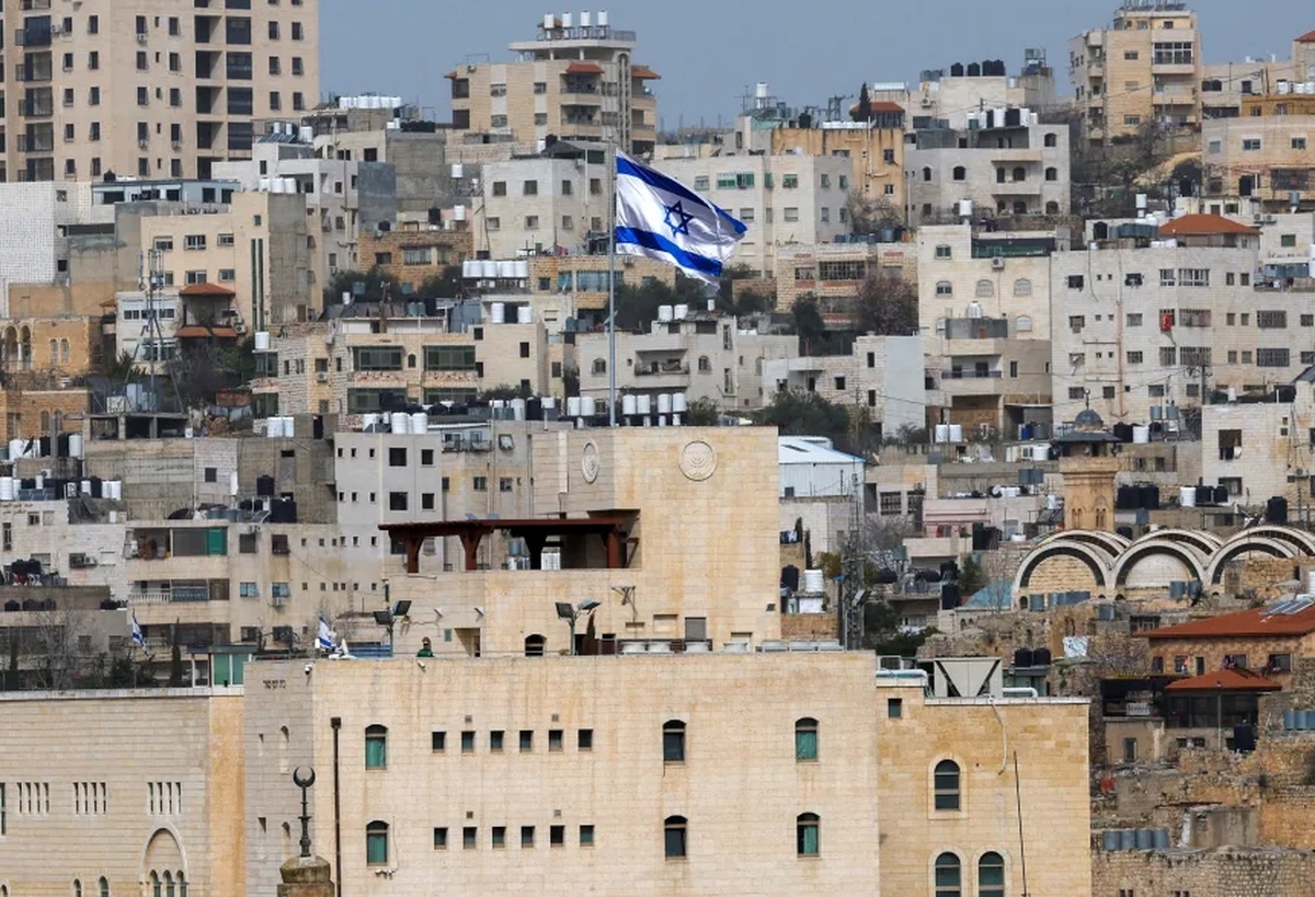 イスラエル人入植地の上に掲げられているイスラエル国旗=パレスチナ自治区ヨルダン川西岸地区ヘブロン/Mussa Qawasma/Reuters