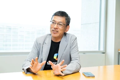 A man in a grey suit jacket talking