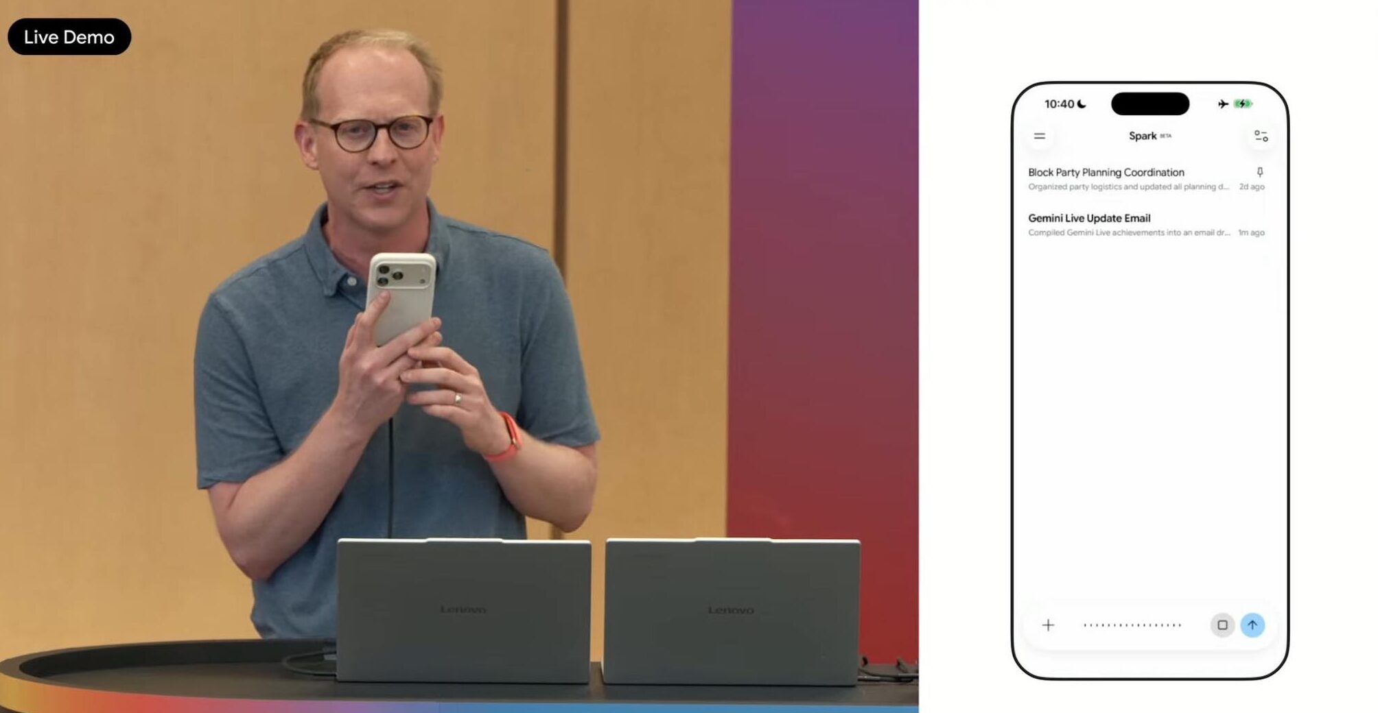 PhoneIslamより:Google I/O 2026カンファレンスで、ある人物がスマートフォンを手にプラットフォームの上に立ち、その前に2台のノートパソコンが置かれ、右側にはメールアプリケーションが表示されたスマートフォンの画面がある。